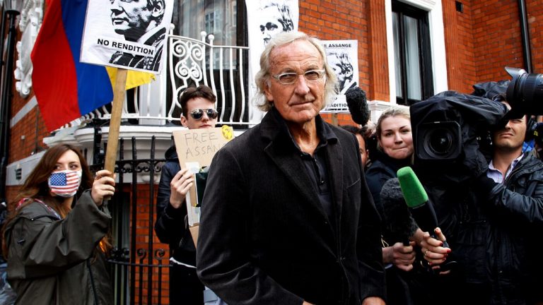 "Ele está isolado e lhe negam as ferramentas para combater as acusações falsas, diz Pilger, na foto em ato por liberdade para Assange" - Mintpress